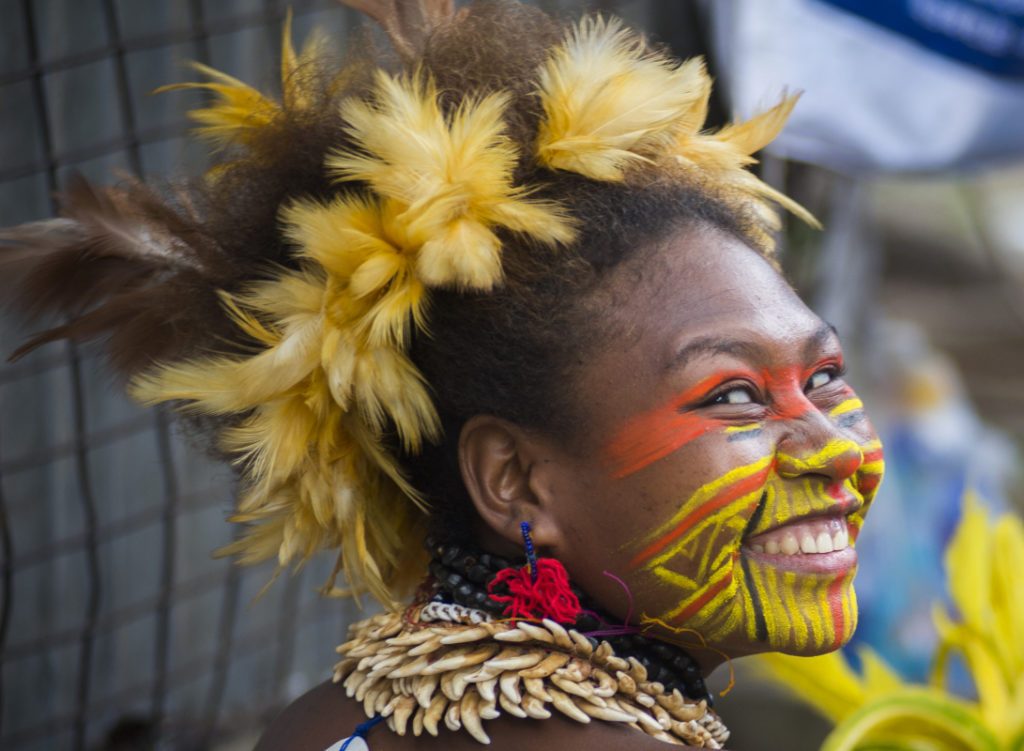 Papua New Guinea Roro Tribe smiling young woman with painted face and headdress ready for dancing