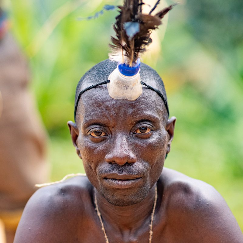 Batwa man wearing parrot feathers adornment for a traditional dance